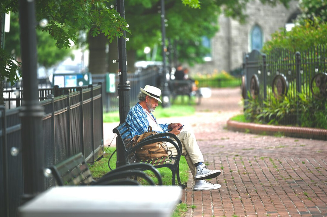 Elderly man sitting on a park bench in the city